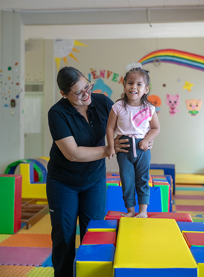 Persona adulta acompañando a una niña en un espacio de rehabilitación